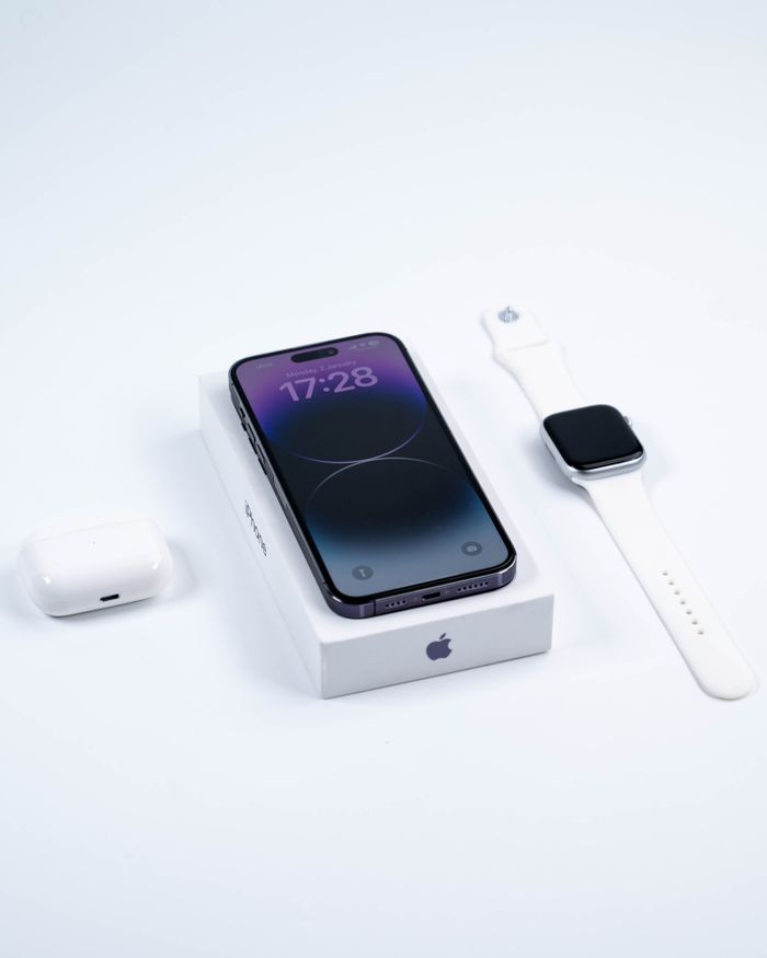 Close-up of a smartphone, smartwatch, and earbuds on a white background emphasizing modern technology.