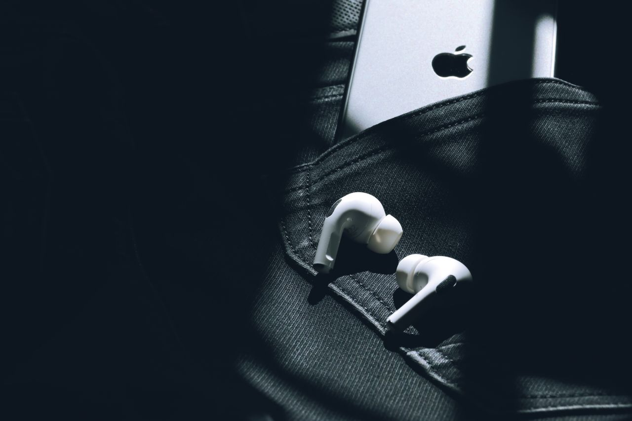 Wireless earbuds and a smartphone in a sunlit pocket, showcasing modern technology.